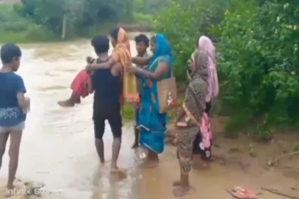 Balrampur Health System : गर्भवती को गोद में उठाकर पार कराया उफनता नाला, 2 KM पैदल चलकर एंबुलेंस तक पहुंचाया